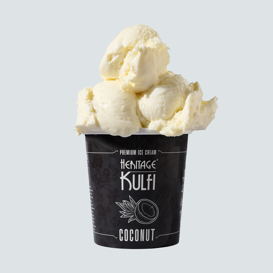 3 scoops of coconut kulfi sit atop a black pint container with a coconut icon on the front