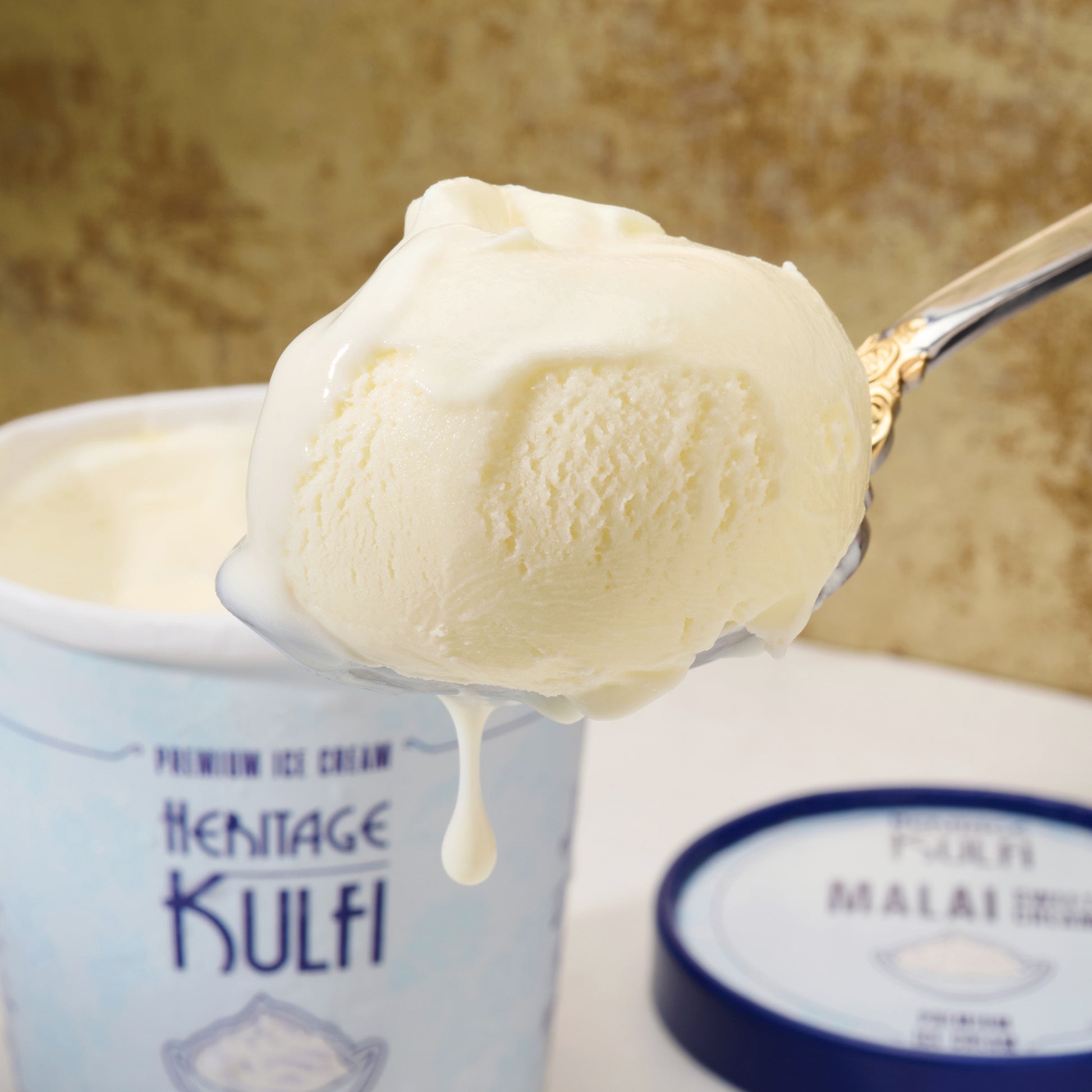 A scoop of creamy kulfi drips from a silver spoon