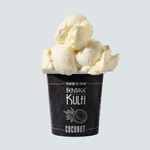 3 scoops of coconut kulfi sit atop a black pint container with a coconut icon on the front