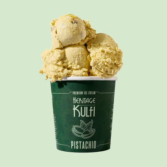 3 scoops of pistachio-specked kulfi sit atop a dark green pint container with a pistachio icon on the front